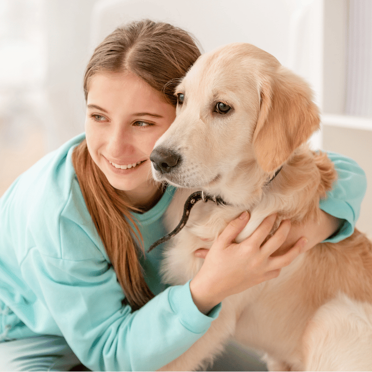 A girl is seen hugging a golden retriever